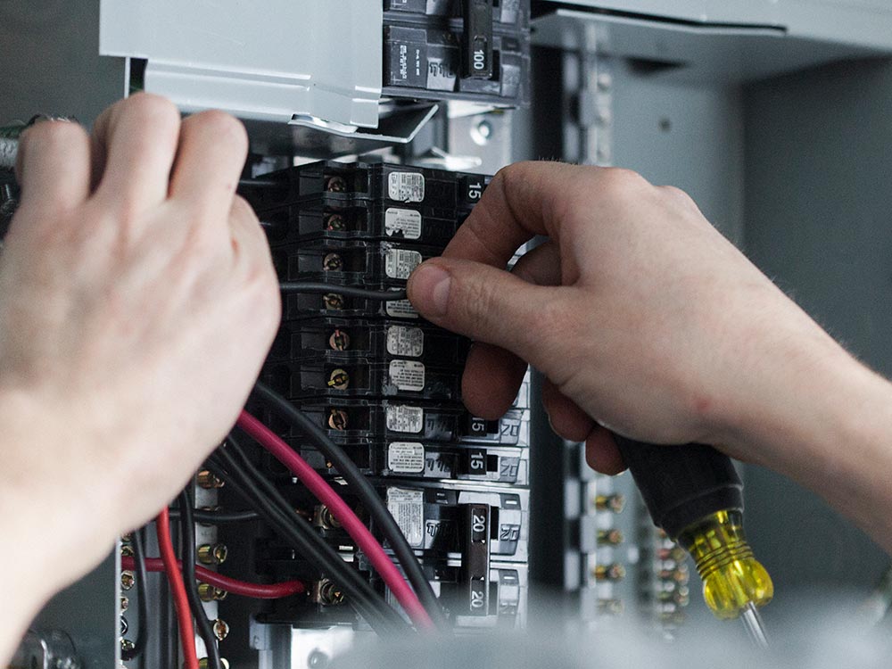 Close up of electrician's hands installing a new breaker.
